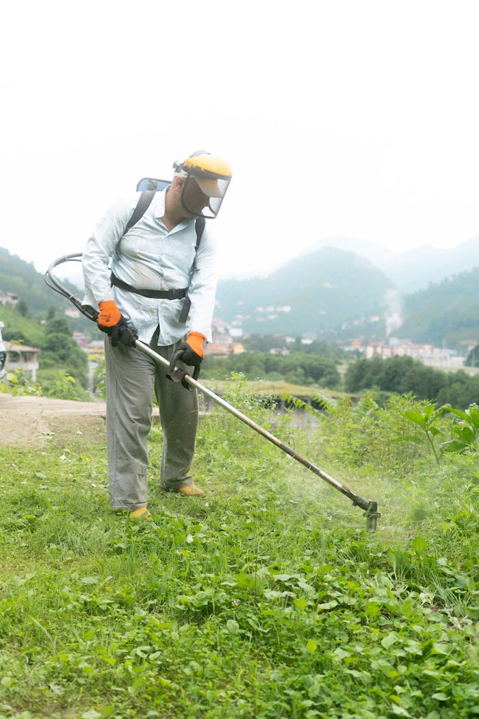 Man mowing grass with safety gear in a green hillside landscape in Rize, Turkey.